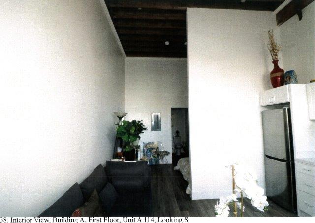 After: Interior view of apartment showing kitchen and bedroom area beyond. Beamed ceiling is retained.